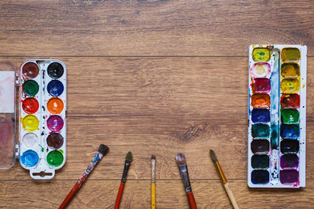 istock Artistic squirrel brush and water paints. Drawing tools for pupils, students, artists .Palitra of twenty-four colors. . Economical and safe material for painting with children. Brushes and watercolor on warm wooden background. 681896000
