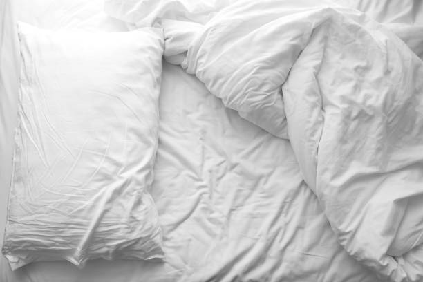 Messy bed. White pillow with blanket on bed unmade. Concept of relaxing after morning. Messy bed. White pillow with blanket on bed unmade. Concept of relaxing after morning. With lighting window. Black and white theme. bed sheets stock pictures, royalty-free photos & images