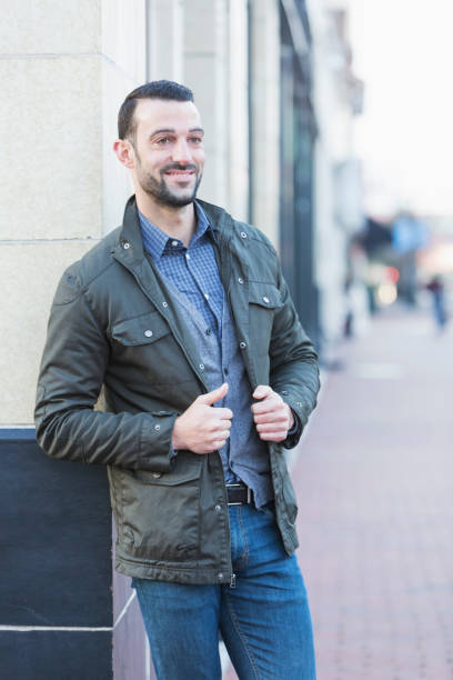istock Young man with beard standing on city street corner 681899374
