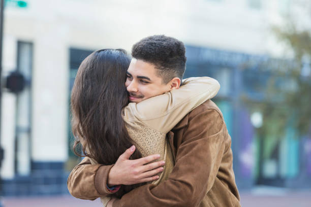 istock Young Hispanic couple embracing on city sidewalk 681899512