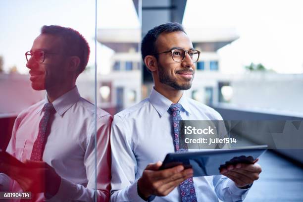 Millenial Geschäftsmann Lehnt Sich Selbstbewusst Auf Eine Dunkle Glaswand Mit Stadtbild Hintergrund Stockfoto und mehr Bilder von Geschäftsmann