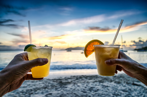 Toasting with tropical drinks on the beach with beautiufl sunset on the ocean