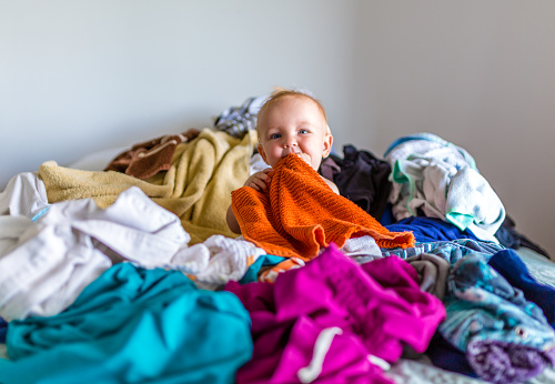 Lindo bebé adorable se sienta en una pila de lavandería en la cama photo