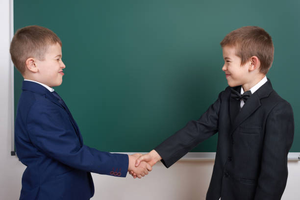 istock elementary school boy near blank chalkboard background, dressed in classic black suit, group pupil, education concept 681967408