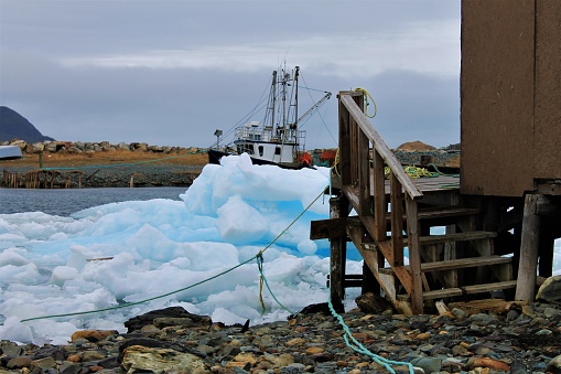 Pack Ice in Ferryland, Newfoundland and Labrador, Canada, April 22, 2017. Looking from the beach around the corner of an outbuilding at the Ice in the bay and a boat in a small patch of open water on the far side.