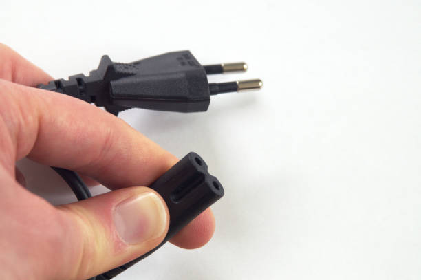 istock hand holding AC mains cord on white background 681975180