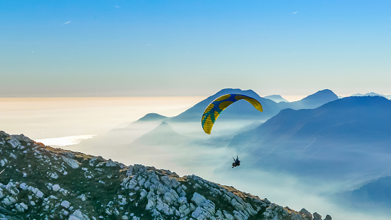 Paragliding tandem flying over the mountains against lake during sunset. Freedom concept. Garda lake, Italian Alps