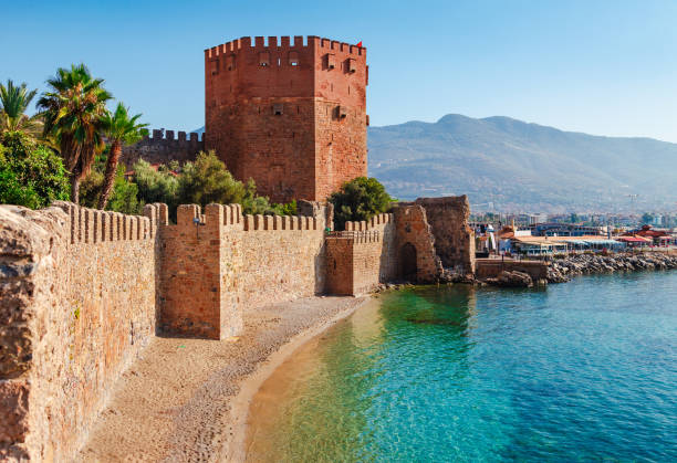Kizil Kule tower in Alanya peninsula, Antalya district, Turkey, Asia. Famous tourist destination with high mountains. Part of ancient old Castle. Summer bright day Kizil Kule tower in Alanya peninsula, Antalya district, Turkey, Asia. Famous tourist destination with high mountains. Part of ancient old Castle. Summer bright day alanya stock pictures, royalty-free photos & images