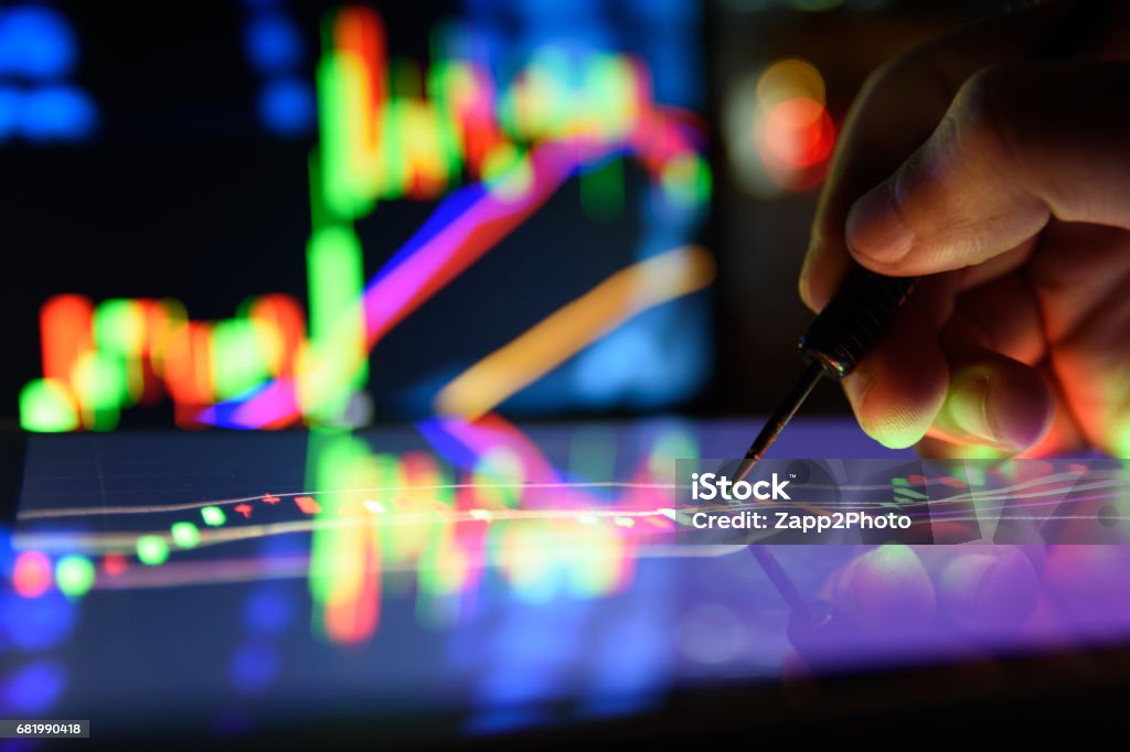 Arrow dart and man finger with Graph Stock market trading tablet screen and laptop's lcd monitor background applied as business and stock concept , forex oil gold trading concept Financial Technology Stock Photo