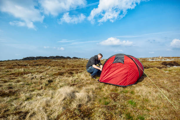 istock Man with red tent in remote moorland setting, Wild Camping. 682001022