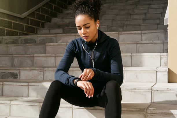 Young female runner checking her pulse Young female runner checking her pulse with an activity tracker after training fitness tracker stock pictures, royalty-free photos & images