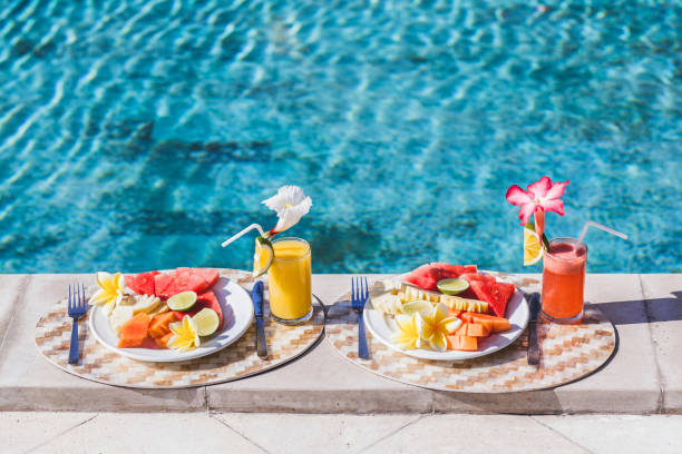 istock Two plates with fresh fruit and two juice with slice orange. Healthy breakfast on poolside in hotel. Plate with papaya, pineapple, watermelon, lime. 682032080