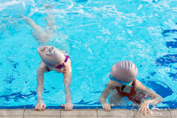 istock happy children kids group at swimming pool class learning to swim 682036558