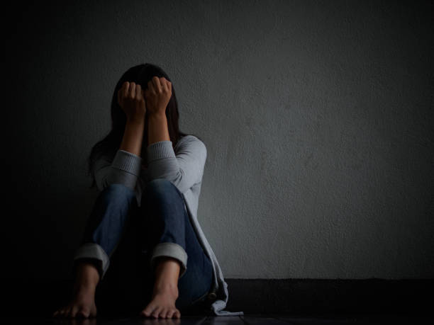 悲しい女性抱擁彼女の膝と泣く。 - うつ 女性 暗い ストックフォトと画像