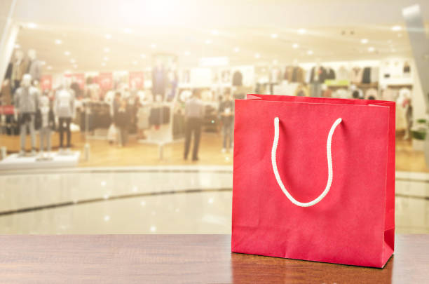 istock Red shopping bag on wooden table over blurred mall 682067128