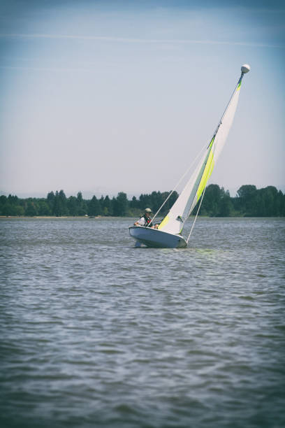 Teenage Boy Learning to Sail in Small Sailboat which is Heeling stock photo