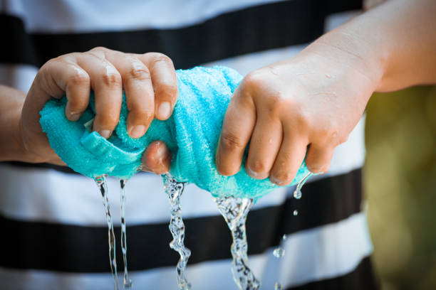 Woman hands squeeze wet blue towel and water drop stock photo