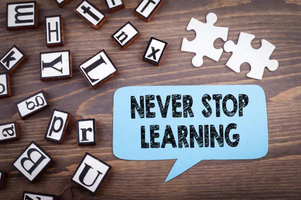 Photo of Never stop learning concept. Speech Bubble on a dark textured wooden background