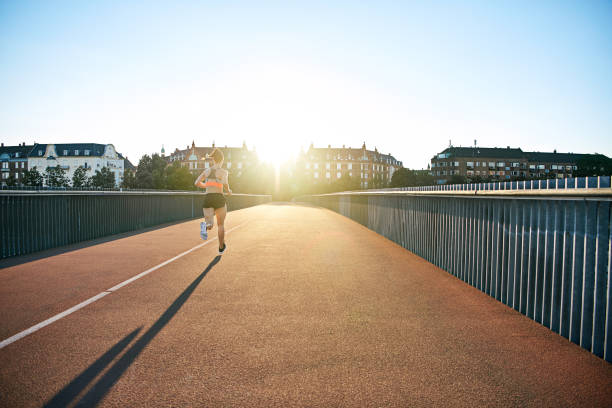 istock Woman running down bridge with long shadow in back 682129806