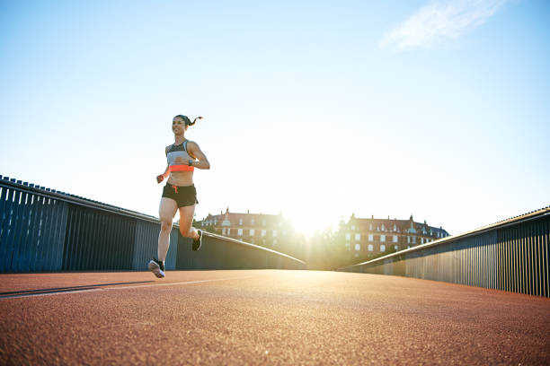 istock Low angle of woman running down bridge with sun 682129850