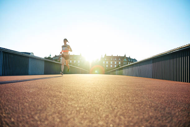 istock Low angle view of woman sprinting along bridge 682129922
