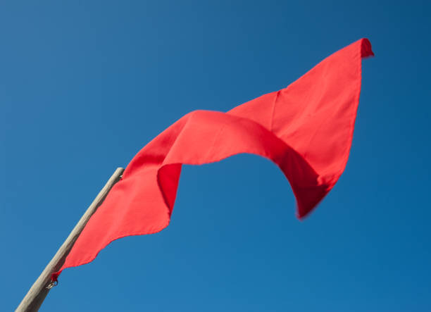 istock Red flag isolated against clear blue sky 682134272