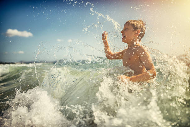 Little boy having fun in sea waves. Big waves are splashing the boy. \n\n