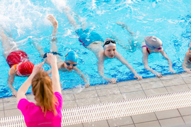 istock happy children kids group at swimming pool class learning to swim 682148638