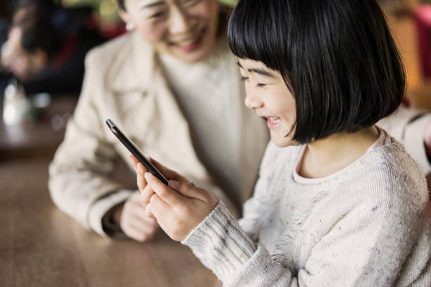 istock Mother and daughter using a smartphone in cafe. 682162988