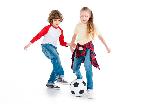 Boy and girl playing football isolated on white, children sport concept