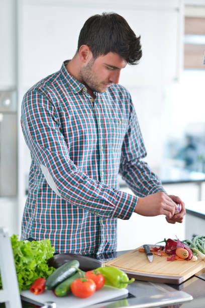 istock Handsome man cooking at home preparing salad in kitchen. 682172040