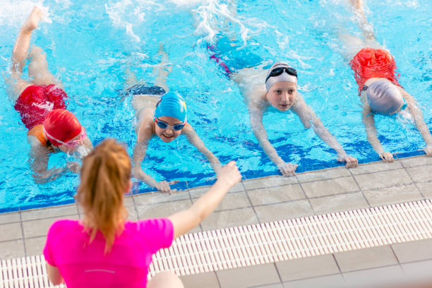 istock happy children kids group at swimming pool class learning to swim 682176024