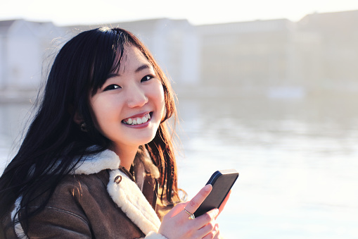 Happy japanese woman tourist taking selfie in popular tourist area, Nyhavn, Copenhagen, Denmark. - February 15, 2017