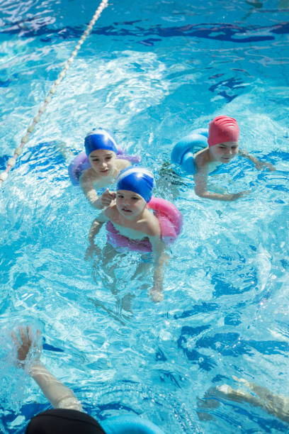 istock happy children kids group at swimming pool class learning to swim 682187004