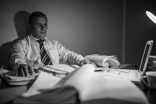 Senior businessman sitting at his desk in his office, finishing the work that must be done.