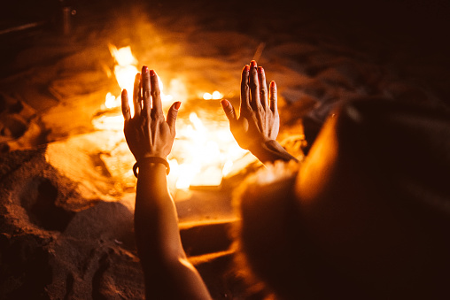 Hands warming up to fireplace at the beach.