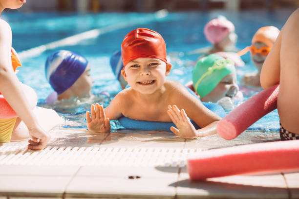 istock happy children kids group at swimming pool class learning to swim 682196948