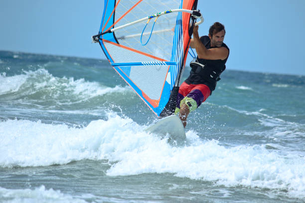 nice mail sportsman windsurfer nice strong mail sportman doing windsurf and looking in front of him seriously and with attention mistral wind stock pictures, royalty-free photos & images