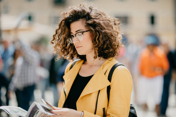 istock Adorable curly haired girl with nose piercing looking at the map 682204032