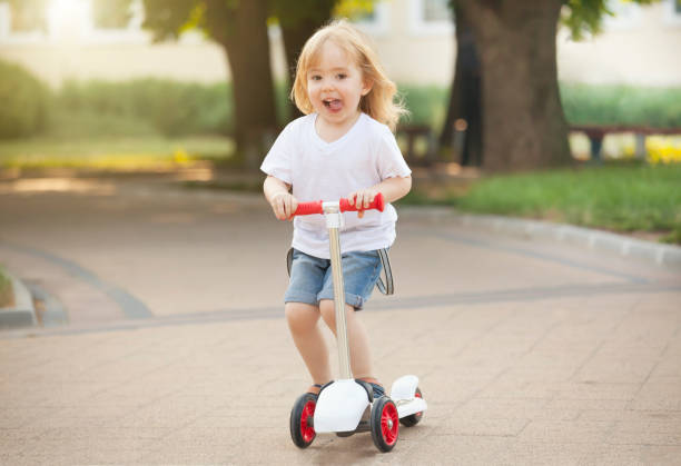 istock Little blond boy riding push scooter in park 682210842