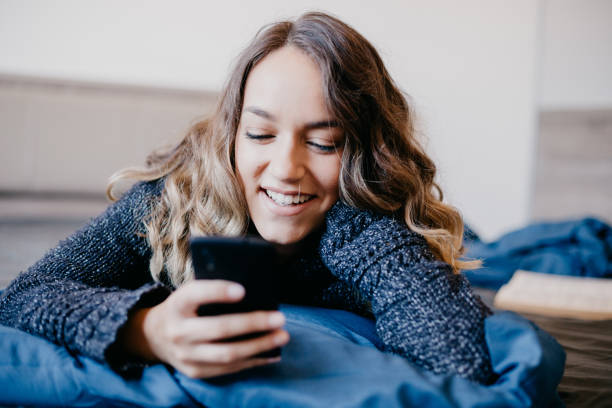 istock Beautiful young woman lying in bed is typing a text message 682213066