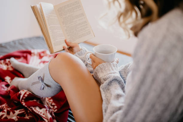 istock Girl drinking coffee while reading a book in the bed 682213204
