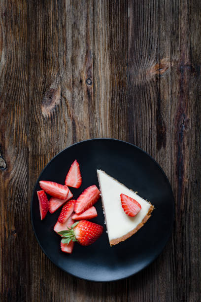 istock Top view of cheesecake with strawberries on a black plate 682213236
