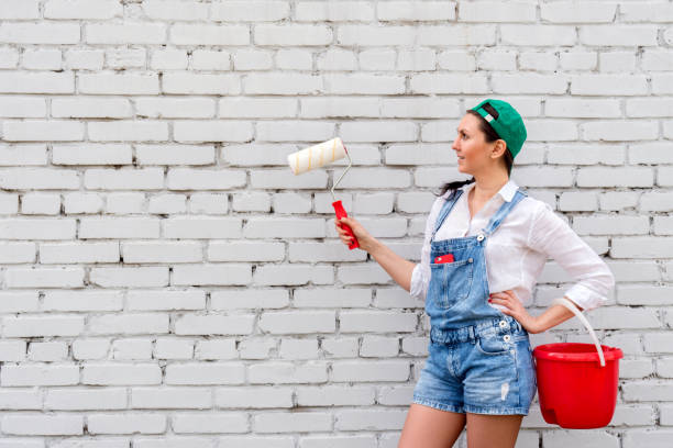 istock girl dressed in denim overalls with paint roller 682216192
