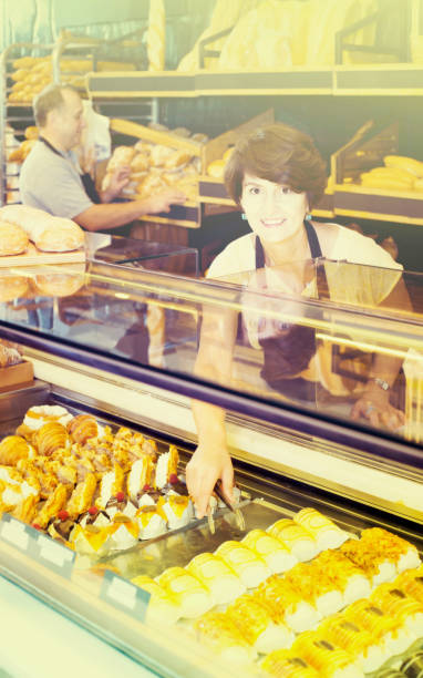 istock staff offering fresh baguettes and buns in bakery 682222730