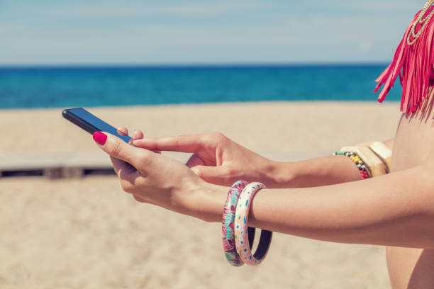 istock Girl holding a cellphone with sea/ocean background. 682223398