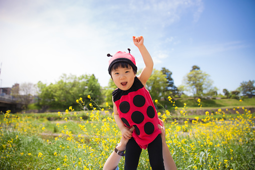 Japanese baby girl flying over flower garden in ladybird clothing