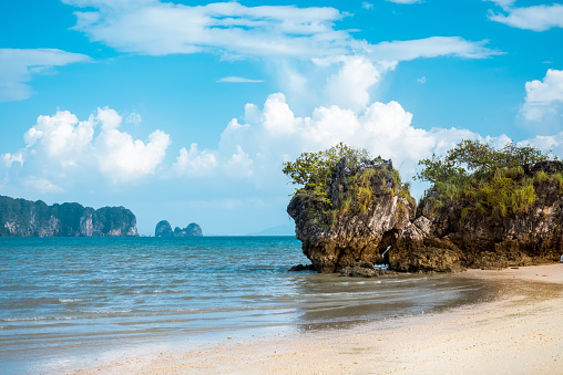 Panorama of a sandy beach and a sea bay with clear wate in El Nido, Palawan island. Blue sky with fluffy clouds in the background.