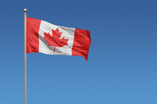 Flag of Canada in front of a clear blue sky
