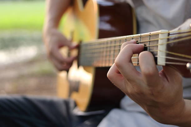 selektywne skupienie palca gitarzysty grającego na gitarze akustycznej na niewyraźnym tle natury. - 20s acoustic guitar adult art zdjęcia i obrazy z banku zdjęć